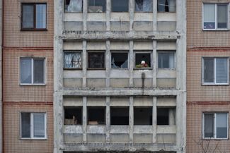 A person stands in a window of the damaged building