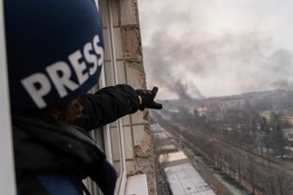 Фотограф Associated Press Евгений Малолетка указывает на дым, поднимающийся от родильного дома после обстрела. Мариуполь, 9 марта 2022 года