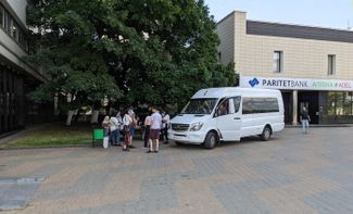 Passengers stand outside a minibus next to the Yubileinaya hotel in Minsk