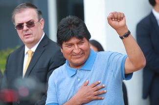 Бывший президент Боливии приветствует журналистов после прибытия в Мексику