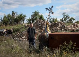 Житель поселка Каменка, 42-летний Юрий Здоровец стоит возле церкви, разрушенной во время российской оккупации