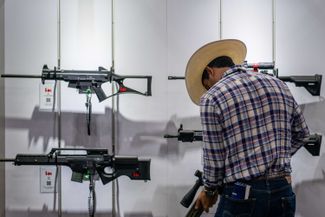 Посетитель ярмарки оружия на ежегодной конференции Национальной стрелковой ассоциации (NRA), которая прошла в Техасе всего через три дня после массового убийства в Ювалде. Хьюстон, Техас, 28 мая 2022 года