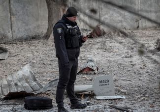 Полицейский возле обломков дрона-камикадзе, выпущенного войсками РФ