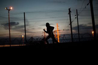 Перебравшийся через забор мигрант бежит к Евротоннелю