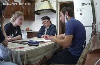 A shot from the security camera inside the crisis shelter during the first visit from the Dagestani police officer named Dalgat. Lawyer Patimat Nuradinova is seated at the end of the table, between Khalimat Taramova and the policeman. 