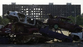 Руины жилых многоэтажек Мариуполя, уничтоженных российскими войсками, на фоне сгоревших машин. О том, что сейчас происходит в Мариуполе, известно мало — только из заявлений оккупационной администрации и российских властей