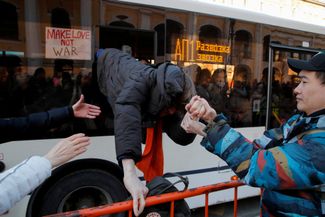 Протестующие помогают задержанному сбежать из автобуса, который перевозил демонстрантов в полицейский участок во время антивоенной акции протеста против российского вторжения в Украину. 27 февраля 2022 года