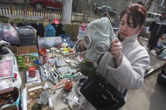 Женщина осматривает противогаз на блошином рынке в Одессе
