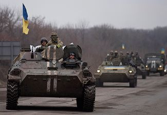 Ukrainian servicemen ride atop armored vehicles with Ukrainian flags, near Artemivsk, eastern Ukraine. March 3, 2015