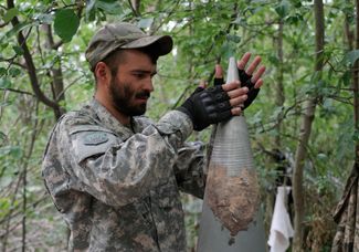 Украинский военнослужащий извлекает детонатор из снаряда российской системы залпового огня «Смерч»