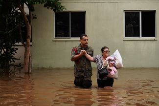 Военнослужащий Вооруженных сил (ВС) Бразилии помогает эвакуироваться жительнице Каноаса, 4 мая