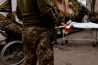 Раненого украинского солдата несут в переоборудованный автобус украинских врачей-добровольцев. С восточной линии фронта под Бахмутом его повезут в госпиталь Днепропетровской области