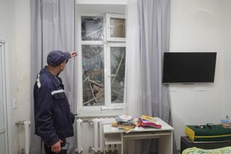 Работник коммунальных служб осматривает квартиру в одном из жилых домов, поврежденных российской ракетой