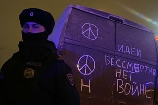 Полицейский у Борисовского кладбища и надпись «идеи бессмертны, нет войне» на грязи фургона