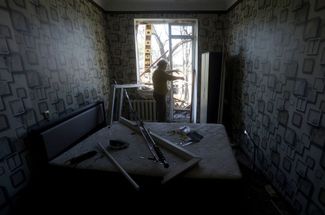 Женщина расчищает завалы в своей квартире, пострадавшей в результате авиаудара. 