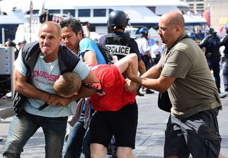 Сотрудники полиции задерживают английского болельщика во время столкновений перед матчем в Марселе. 11 июня 2016 года.