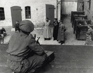 Британский солдат наблюдает за сдачей в плен членов правительства Дёница. Слева направо: Альберт Шпеер, Карл Дёниц, Альфред Йодль. 23 мая 1945 года