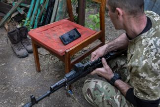 Недавно мобилизованный военнослужащий ВСУ на фронте смотрит видеоинструкцию по сборке-разборке и чистке оружия