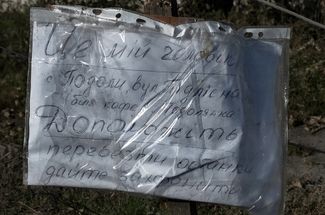 Лист бумаги с надписью возле тела погибшего жителя Купянска-Узлового: «Это мой муж.Село Подолы ул. Подлесная (возле кафе „Подолянка“). Помогите перевезти останки. Дайте захоронить»