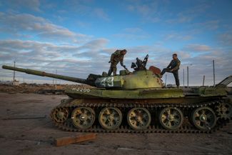 Украинские военные осматривают подбитый российский танк в селе Чернобаевка. В середине ноября силы ВСУ вернули контроль над селом, за которое шли продолжительные бои