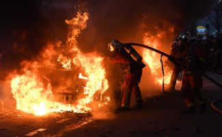 Пожарные тушат один из подожженных во время акции автомобилей