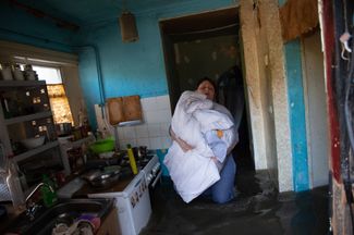 A Kherson resident carries bedding out of her flooded home. 