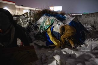 Луисвилль, штат Кентукки, США. Работник социальной службы доставляет вещи людям, живущим в лагере для бездомных. 23 декабря 2022 года
