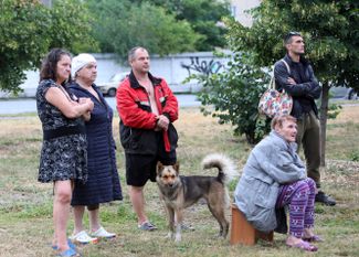 Жители жилой шестиэтажки в Харькове, поврежденной российской ракетой утром 11 июля, наблюдают за ходом спасательной операции