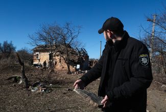 Сотрудник полиции осматривает обломки поврежденного частного дома в Орехове