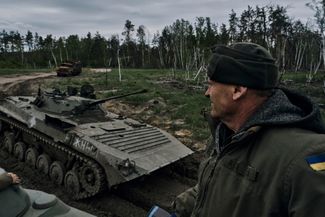 Боец ВСУ наблюдает за проезжающим украинским БТР на позициях под Кременной