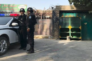 Police near the wall of a reeducation camp in Xinjiang, November 2, 2017