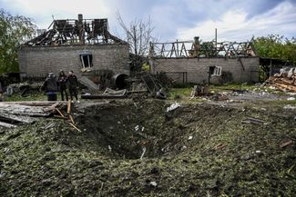 Жители Краматорска Донецкой области стоят у воронки рядом с разрушенным домом