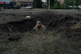Украинский полицейский изучает место взрыва российских снарядов, чтобы определить, какими боеприпасами была совершена атака на Краматорск