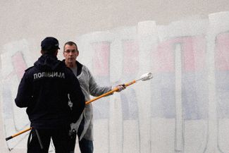 Владимир Арсеньевич закрашивает мурал «Когда войска на Косово вернутся…» в центре Белграда. 18 февраля 2023 года