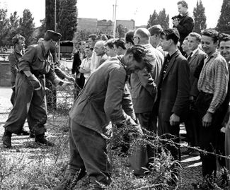 Солдаты армии ГДР ставят первое проволочное заграждение на улице Берлина. 13 августа 1961 года