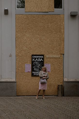 Харьковчанка стоит у кофейни с заколоченными окнами в центре города