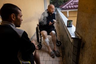 Пациенты киевского госпиталя — 22-летний Владимир (слева) и 40-летний Денис (справа) — курят на балконе больницы