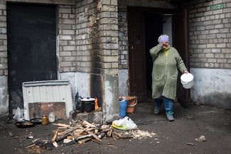 Женщина готовит еду на огне около своего дома