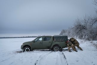 Бойцы ВСУ толкают застрявшую в снегу машину