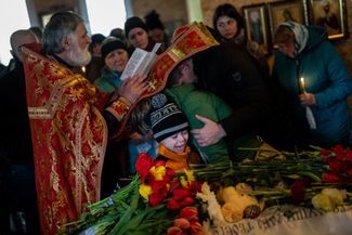 Младший брат убитой российским обстрелом Софии Шульги плачет у ее гроба во время отпевания
