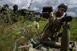 Украинский военный готовится обстреливать российские позиции. Он устанавливает взрыватель на снаряд для гаубицы M777, отправленной в Украину властями США