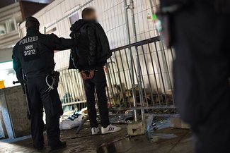 Полицейский обыскивает подозреваемого в районе вокзала в Кельне. 5 января 2016 года.