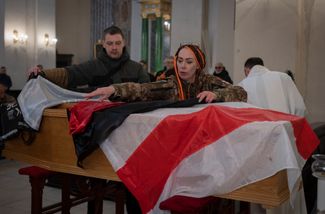 Друзья накрывают гроб добровольца Эдуарда Лобау флагом свободной Беларуси. Лобау, воевавший на стороне Украины с 2015 года, погиб в начале февраля в Донецкой области