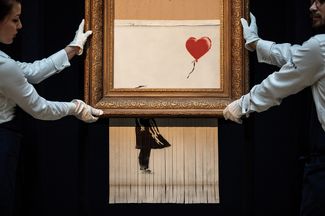 Картина Бэнкси, которая была порезана устройством, спрятанным в раму, после того как ее продали на аукционе за миллион фунтов стерлингов. 12 октября 2018 года.<br>