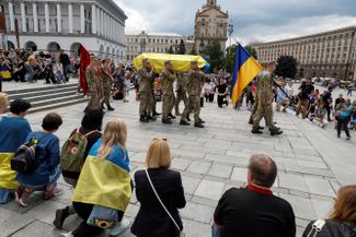 Почетный караул несет гроб с телом Романа Ратушного, погибшего 9 июня под Изюмом. 24-летний Ратушный был известным киевским активистом, участником Евромайдана. Одной из его инициатив была защита от застройки Протасова Яра — зеленой зоны в черте города. Участвовал в <a href="https://meduza.io/short/2021/03/21/protestuyuschie-podzhigayut-vyvesku-prezident-ukrainy-na-zdanii-ofisa-vladimira-zelenskogo-fotografiya" rel="noopener noreferrer" target="_blank">акциях поддержки</a> лидера одесского «Правого сектора» Сергея Стерненко, после которых попал под домашний арест по подозрению в хулиганстве. Во время войны Ратушный участвовал в боях под Киевом, был в составе 93-й ОМБр «Холодный овраг», воевал за Тростянец, Сумы, принимал участие в боях под Изюмом. На прощание с Ратушным пришли сотни людей, в том числе мэр Киева Виталий Кличко