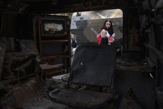 Девушка заглядывает внутрь сожженной бронемашины, ставшей экспонатом выставки захваченной российской техники на Крещатике в Киеве