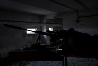 Снайпер с позывным Курт проверяет свой телефон после выстрела по российским позициям