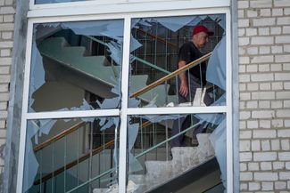 Мужчина поднимается по лестнице в разрушенной гимназии.