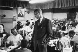 Малкольм Икс разговаривает с темнокожей посетительницей ресторана в «черном» квартале Нью-Йорка Гарлеме. Первая половина 1960-х годов