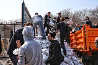 Волонтеры и мешки с песком, которые станут частью городских укреплений. 25 марта 2022 года